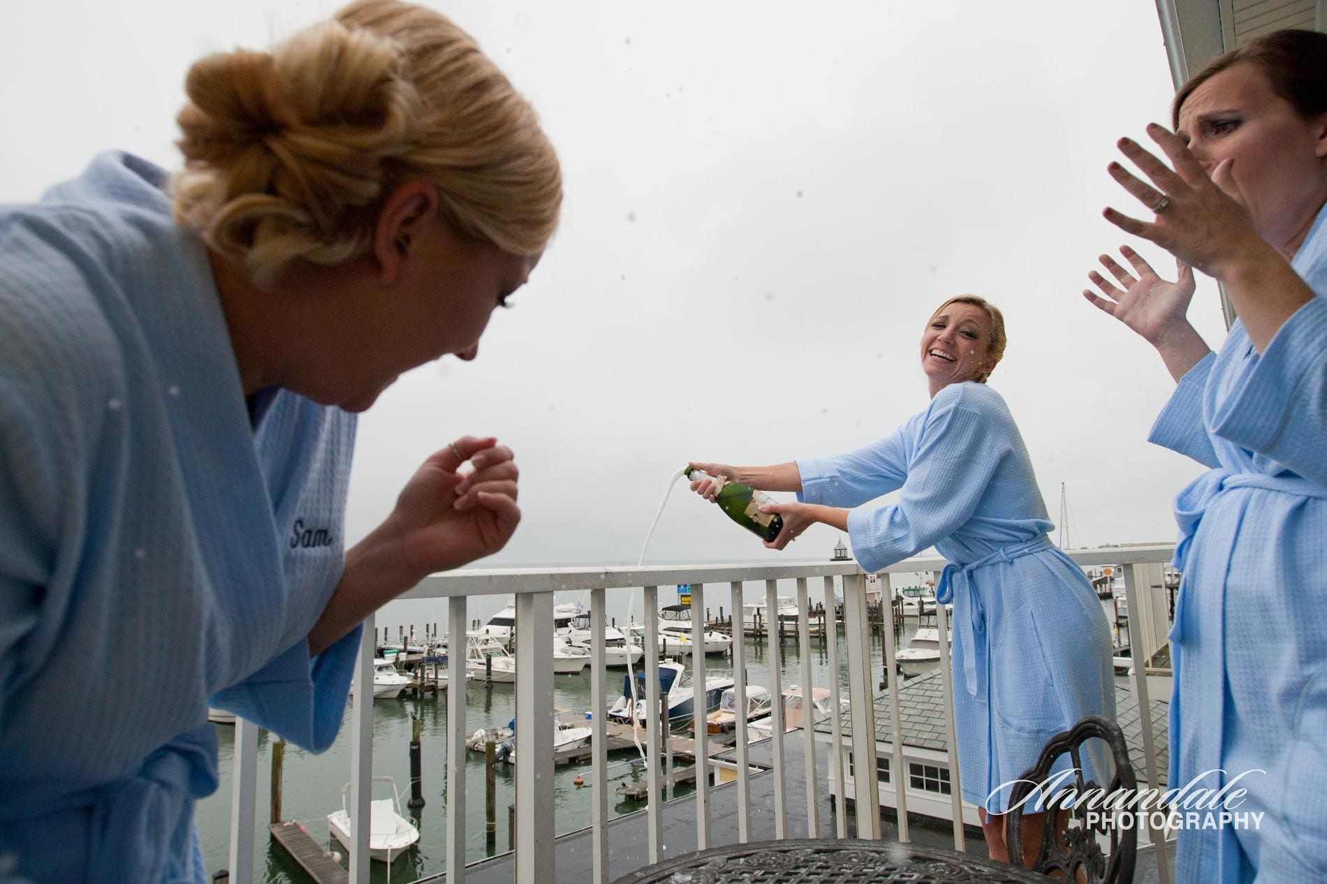 Woman opening champagne on deck overlooking marina.