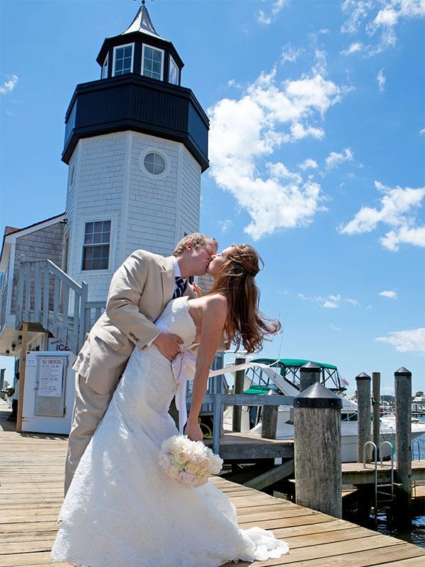 Bride and groom kissing near lighthouse.